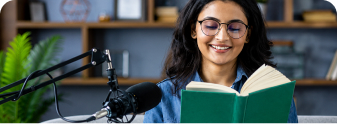 An author sitting with a microphone and a book, preparing a manuscript for digital publishing.