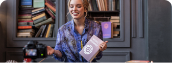 A creator holding up a published book to build an author brand and plan a book launch strategy.