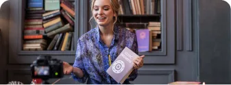 A creator holding up a published book to build an author brand and plan a book launch strategy.